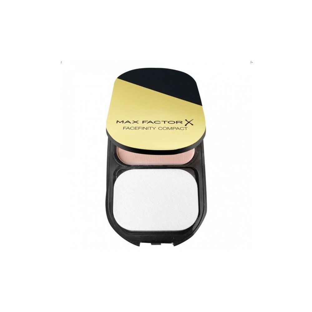 An open Max Factor X Facefinity Compact powder foundation compact, showing a dual-tone gold and black lid with the brand name printed in black, and a dual-toned pressed powder foundation in shades of pink and white.