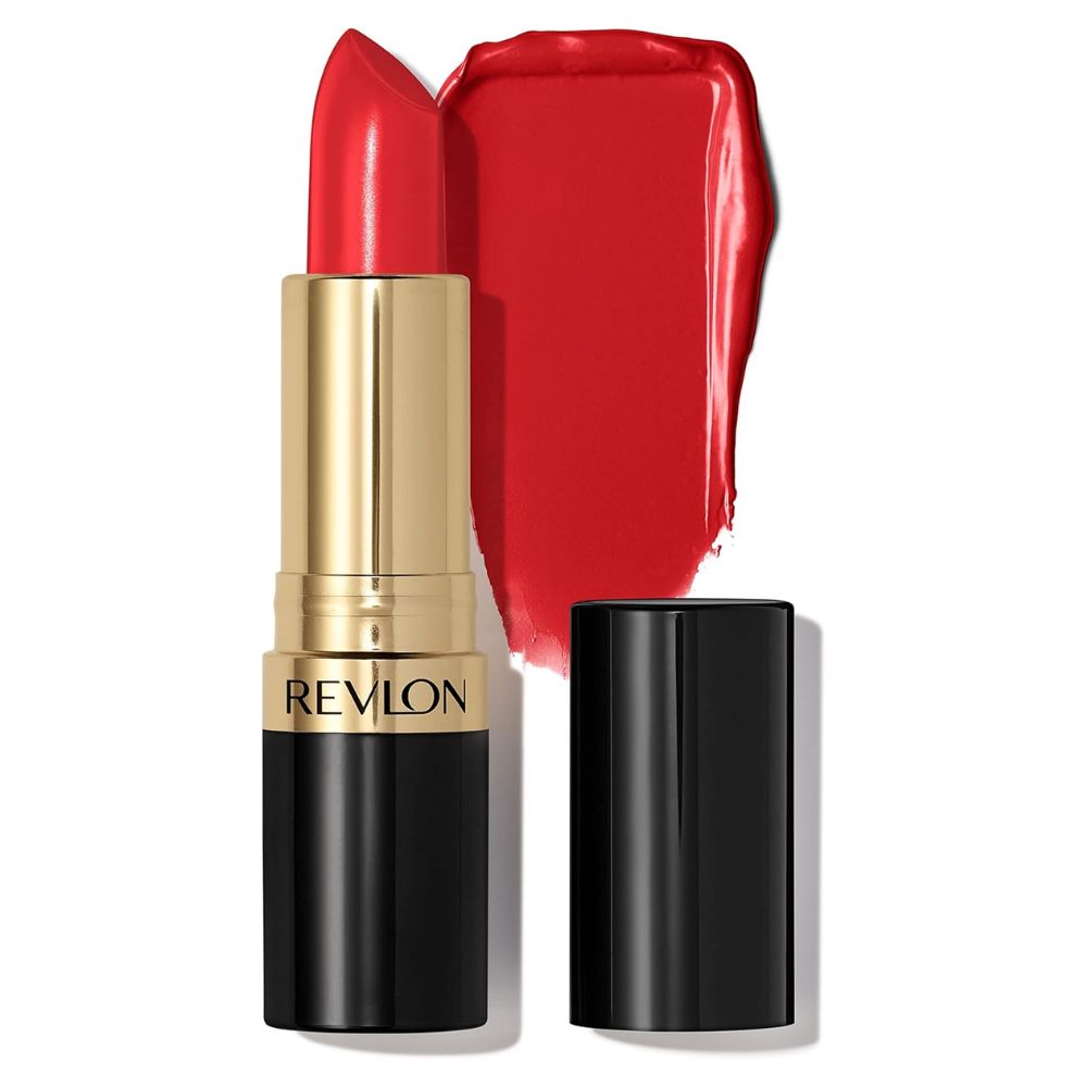 A Revlon lipstick in a bright red shade, shown with its gold and black tube, a detached black cap, and a glossy smear of the red lipstick behind it on a white background.